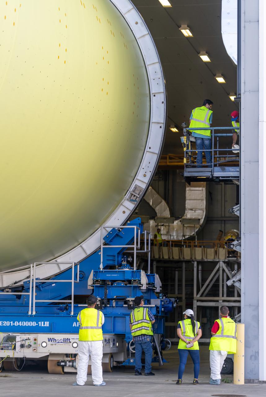 Teams move a liquid hydrogen tank for NASA’s SLS (Space Launch System) rocket out of a priming cell and into an adjacent cell on May 20 at the agency’s Michoud Assembly Facility in New Orleans. Inside the cell, the tank, which will be used on the core stage of NASA’s Artemis III mission, will receive its thermal protection system.  The thermal protection system, or spray-on foam insulation, provides protection to the core stage during launch. It is flexible enough to move with the rocket yet can withstand the aerodynamic pressures as the SLS accelerates from 0 to 17,500 mph and soars to more than 100 miles above the Earth. This third-generation insulation is more environmentally friendly and keeps the cryogenic propellant, which powers the rocket’s four RS-25 engines, extremely cold (the liquid hydrogen must remain at minus 423 degrees Fahrenheit/253 degrees Celsius) to remain in its liquid state. When applied the thermal protection system is a light-yellow color, which “tans” once exposed to the Sun’s ultraviolet rays, giving the SLS core stage its signature orange color.